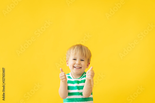 Portrait of happy child against yellow background. Summer vacation concept