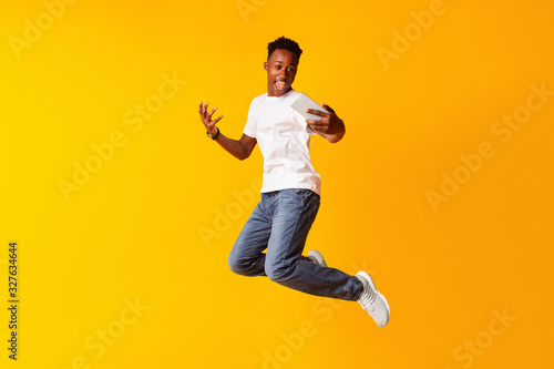 African guy jumping for connecting the internet on his cell phone