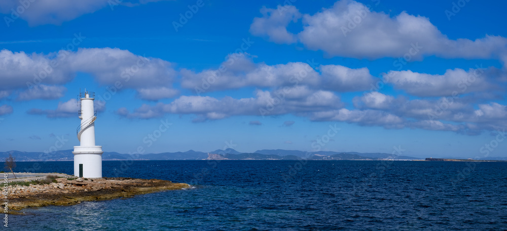 White lighthouse in La Savina, Formentera island, with the island of Ibiza in the background, Spain