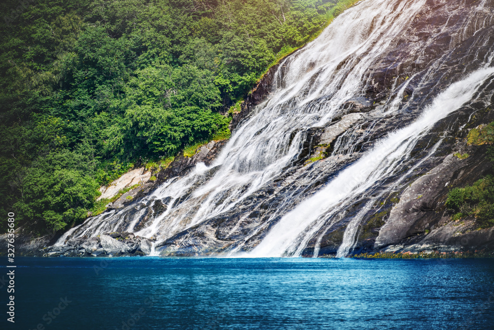 Panoramic beautiful deep forest waterfall in norway near blue ocean. Waterfalls mountain view close up.