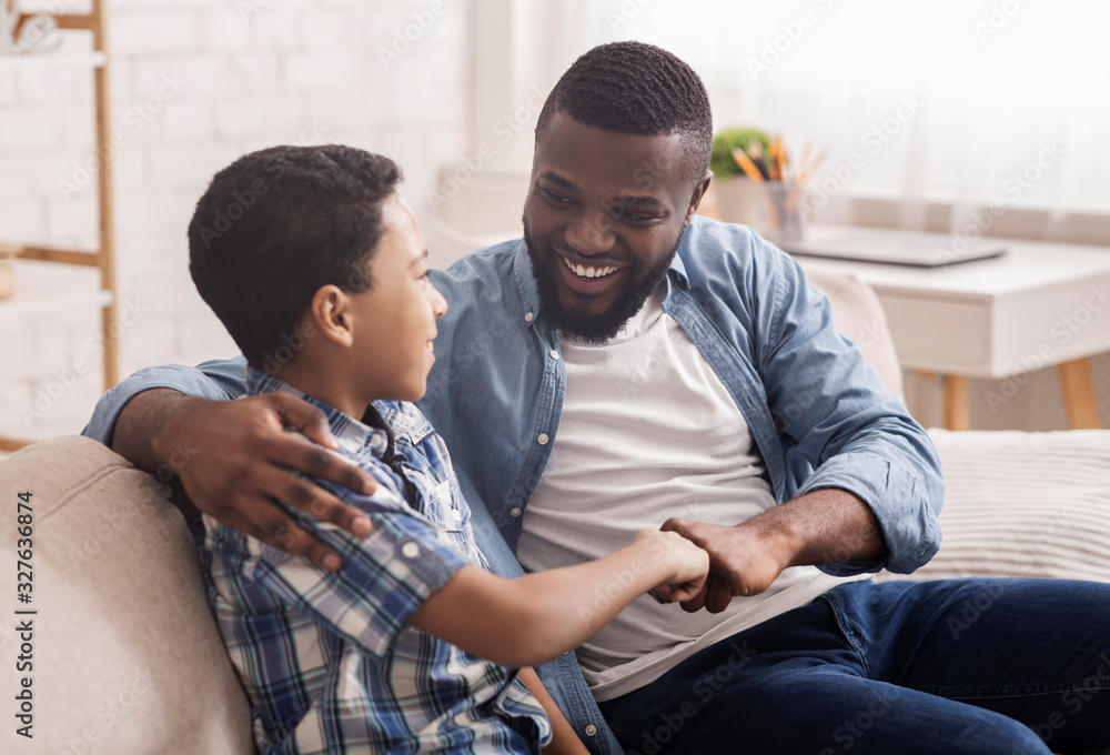 Cheerful Black Boy Bumping Fists With His Dad At Home Cheerful Black Boy Bumping Fists With His Dad At Home