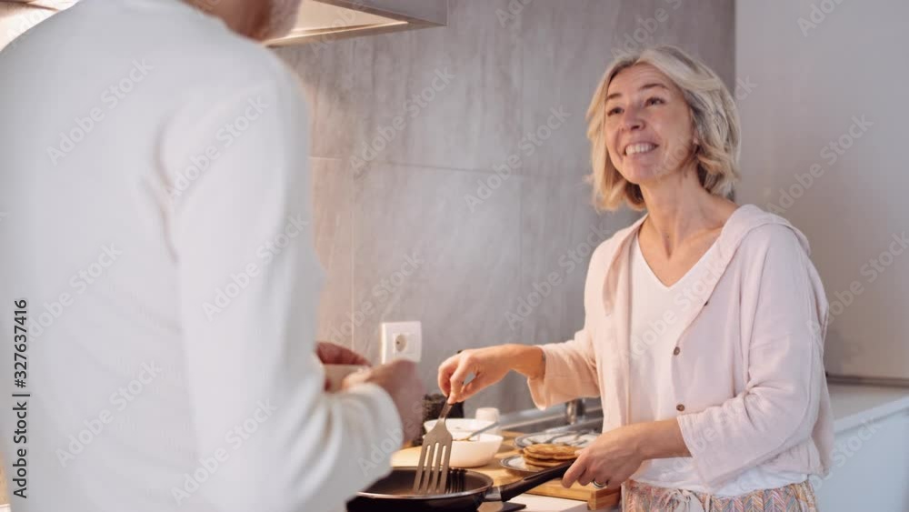 Slow motion shot of mature couple preparing breakfast in kitchen Slow motion shot of mature couple preparing breakfast in kitchen