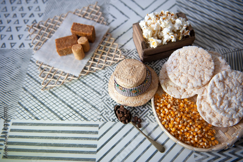 Popcorn, popcorn, straw hat, sweet paçoquinha, kid's foot, traditional ingredients in Brazilian June party. Clear background. Seen from the top. Horizontal. Space for your text.