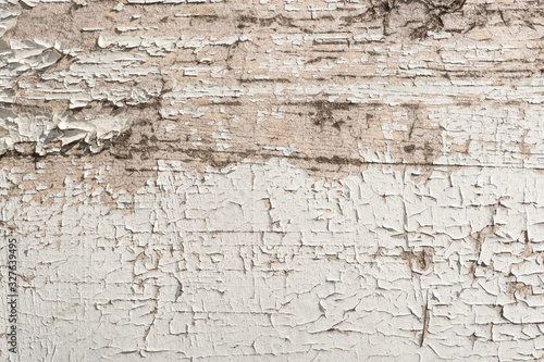 Old peeling cracked weathered white paint on wall of rural house close up. Wood grunge texture background for your design