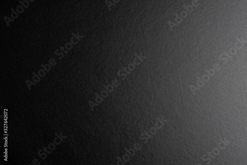 Black background made of real black paper with a matt fibrous structure, illuminated by a soft light from the right.