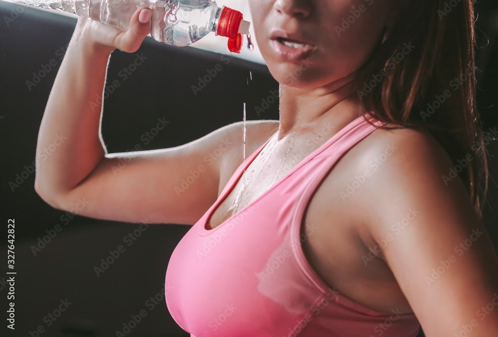 Closeup of wet sexy attractive fitness girl drinking water from bottle