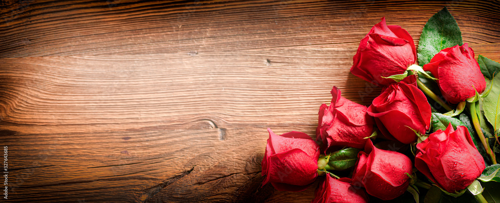 Red roses on vintage old wooden board.  Valentines day web wide rose banner