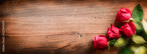 Red roses on vintage old wooden board.  Valentines day web wide rose banner