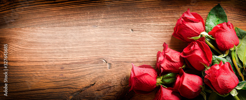 Red roses on vintage old wooden board.  Valentines day web wide rose banner