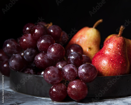 bunch of purple grapes and ripe red pear fruits on plate