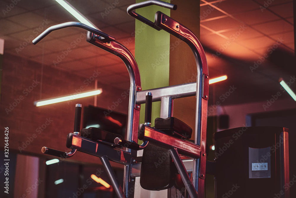 Metallic parallel bar machine standing in an empty modern fitness center. Sportive gym equipment. Metallic parallel bar machine standing in an empty modern fitness center. Sportive gym equipment.