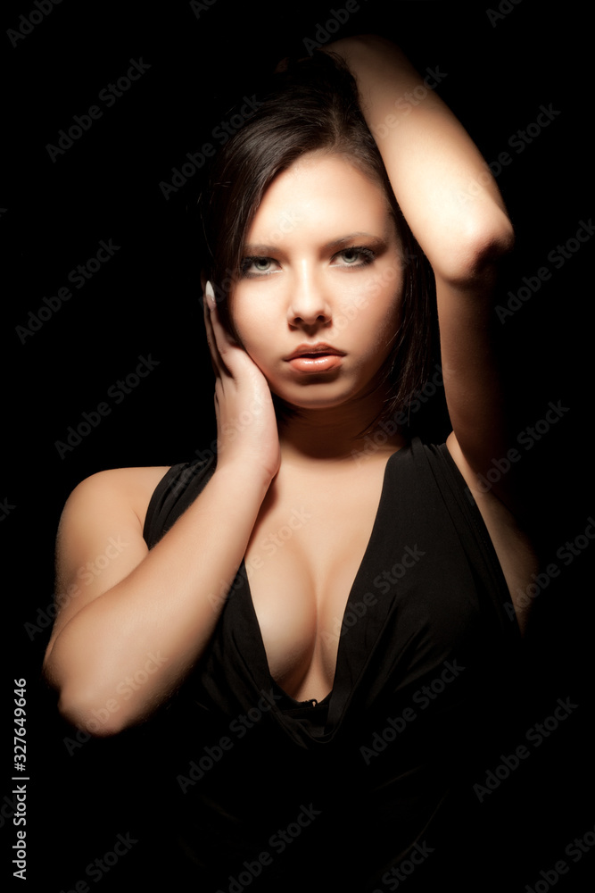 Fototapeta premium Cute serious caucasian young girl posing standing on a black background. Concept of a sense of style and femininity. Advertising space