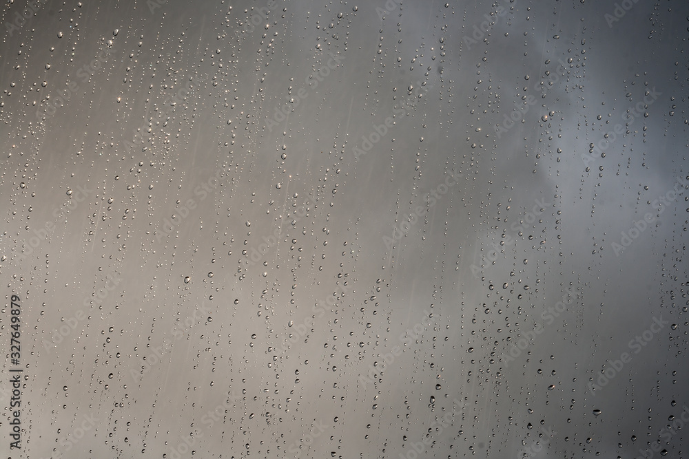 shinny rain droplets on a window, dark clouds in the background shinny rain droplets on a window, dark clouds in the background