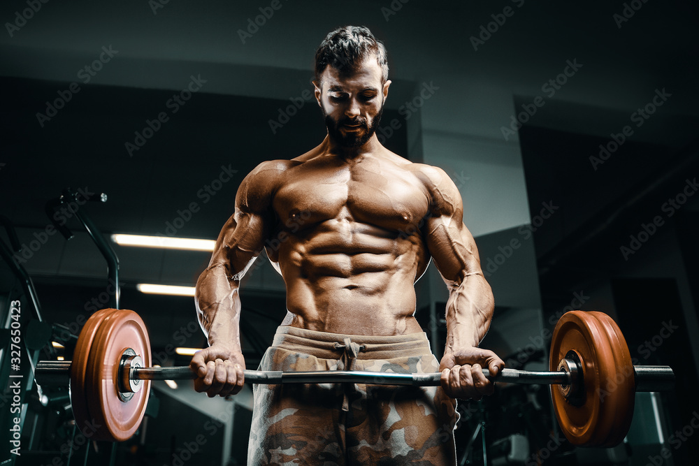 Bodybuilder strong man pumping up biceps muscles Bodybuilder strong man pumping up biceps muscles