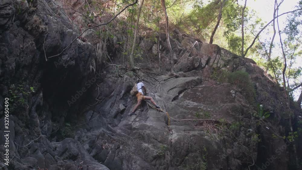 Young man rope climbing rocky cliff in forest in mexico, slow motion Young man rope climbing rocky cliff in forest in mexico, slow motion