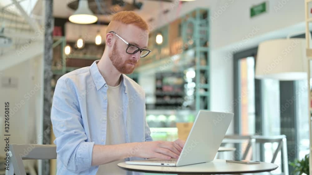 Professional Redhead Man using Laptop in Cafe Professional Redhead Man using Laptop in Cafe