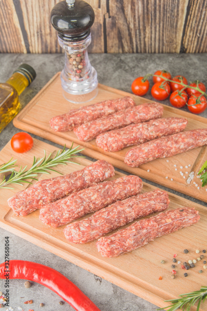 Raw beef sausages. Mititei - Romanian cuisine, on wooden boards with spices. 