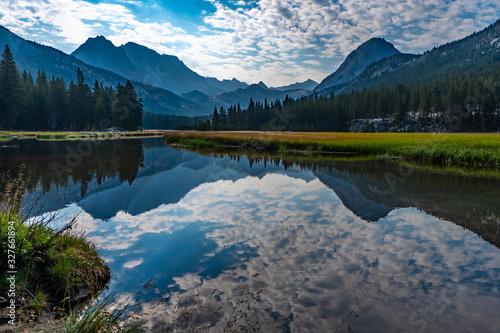 Fototapeta Naklejka Na Ścianę i Meble -  Dramatic Sky over McClure Meadows and reflection in the calm river along the PCT - Pacific Crest Trail, Evolution Valley, King Canyon National Park, Sierra Nevada Mountains, California