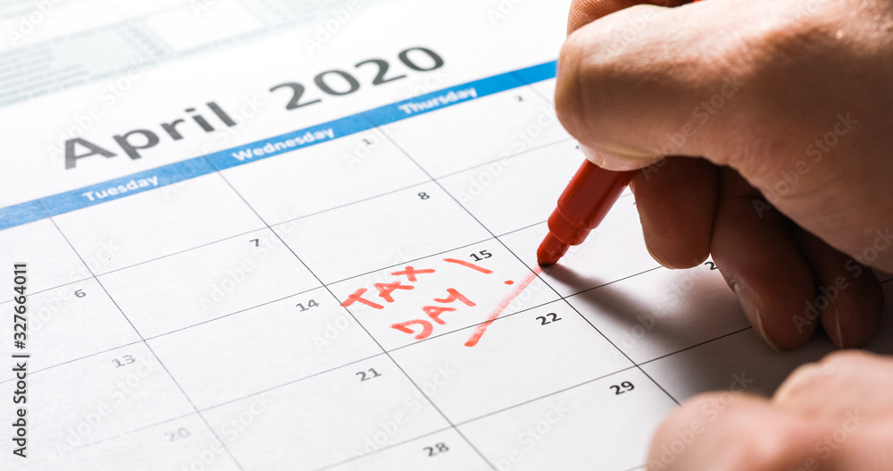 Writing tax day on 2020 April 15 calendar with red marker. Deadline for 1040 form return. Writing tax day on 2020 April 15 calendar with red marker. Deadline for 1040 form return.