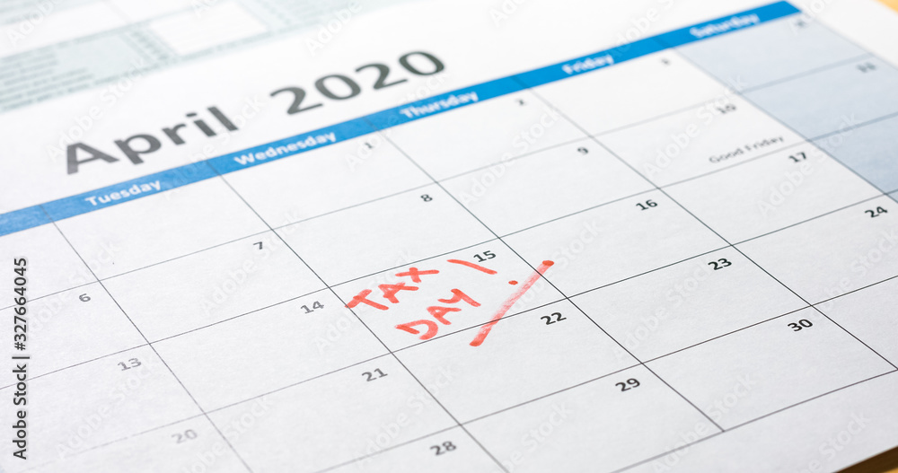 Writing tax day on 2020 April 15 calendar with red marker. Deadline for 1040 form return.
