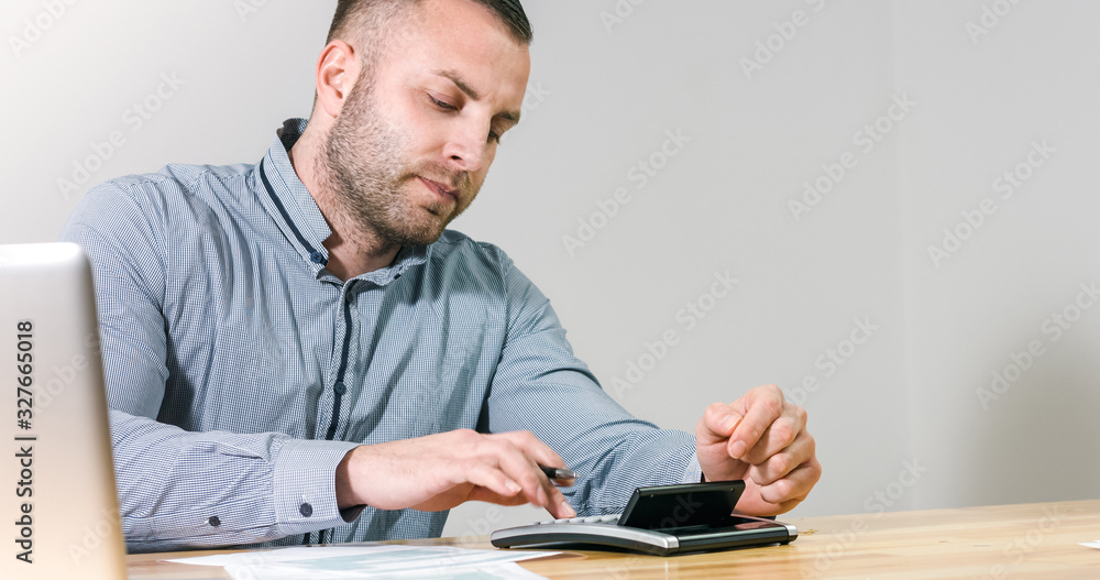 Businessman filling 1040 individual tax form with calculator at office desk. - obrazy, fototapety, plakaty 