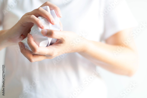 A person uses hands crumple a white paper before dropping to a bin on white background with copy space  selected focus.