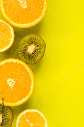 Fruit frame. Colorful fresh citrus fruits on a light green background. Orange  tangerine  lemon and kiwi are cut in half. Flat lay  top view  copy space.