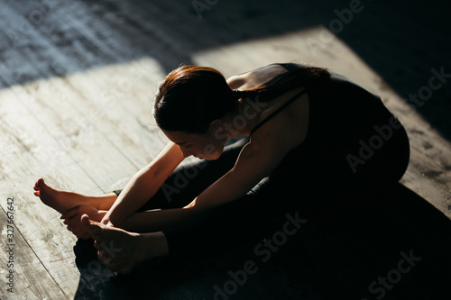 Girl is doing stretching exercise. Yoga class in black sportswear.