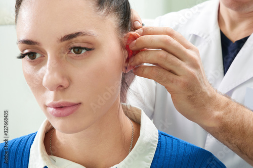 Plastic surgeon examines ear of patient before plastic surgery photo