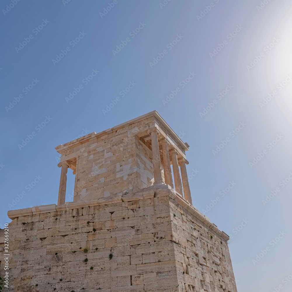 Athens Greece, Athena Nike (victorious) small temple with ionian style columns, standing by the entrance of Acropolis under crystal clear blue sky and sun rays