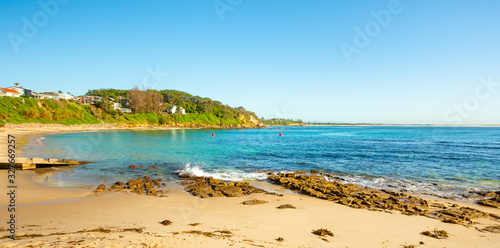Fototapeta Naklejka Na Ścianę i Meble -  A scenic wide angle landscape view of a beautiful calm beach in NSW, Australia on a stunning day with blue sky