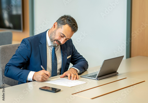 A male employee filling out contracts and forms at the office desk