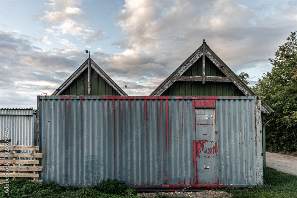 Old and rusty metal cargo container infornt of a farm building Old and rusty metal cargo container infornt of a farm building