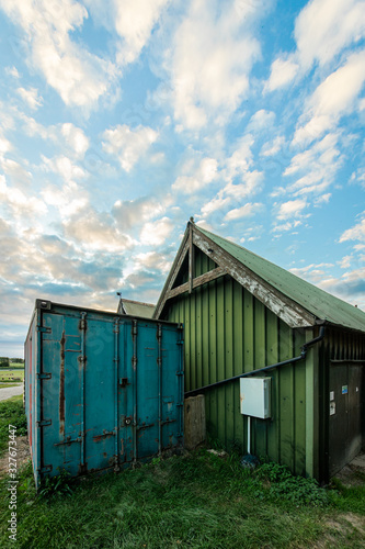 Green farm building and blue cargo container.