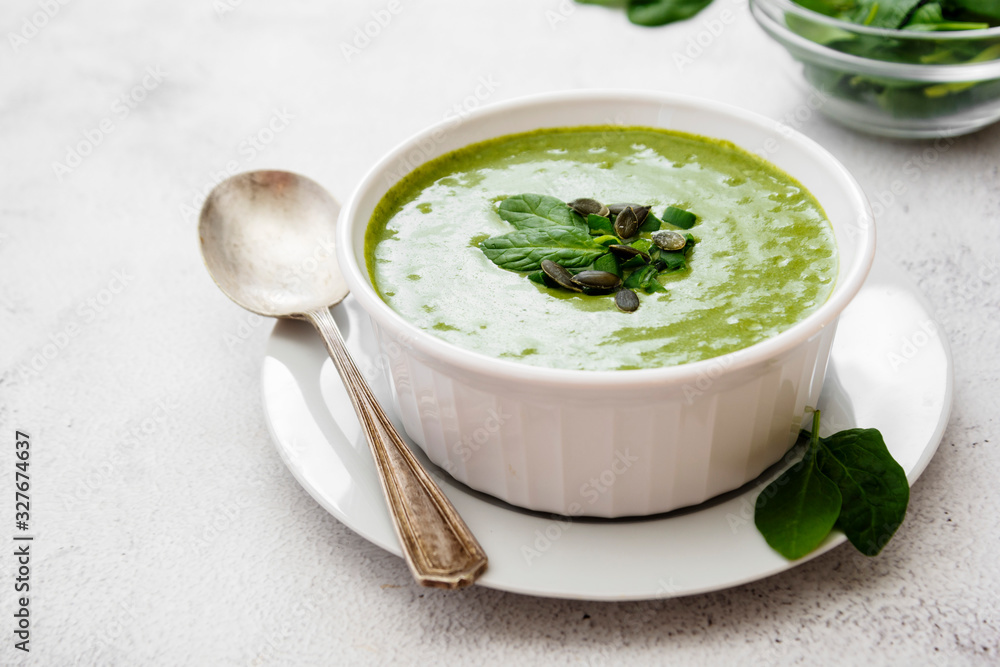 Creamy green spinach soup in a white bowl, spring healthy green creamy soup. Detox, dieting or clean eating food. Creamy green spinach soup in a white bowl, spring healthy green creamy soup. Detox, dieting or clean eating food.
