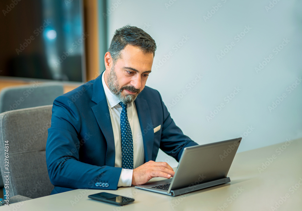 A suit-wearing, bearded and handsome employee who trades on his computer A suit-wearing, bearded and handsome employee who trades on his computer