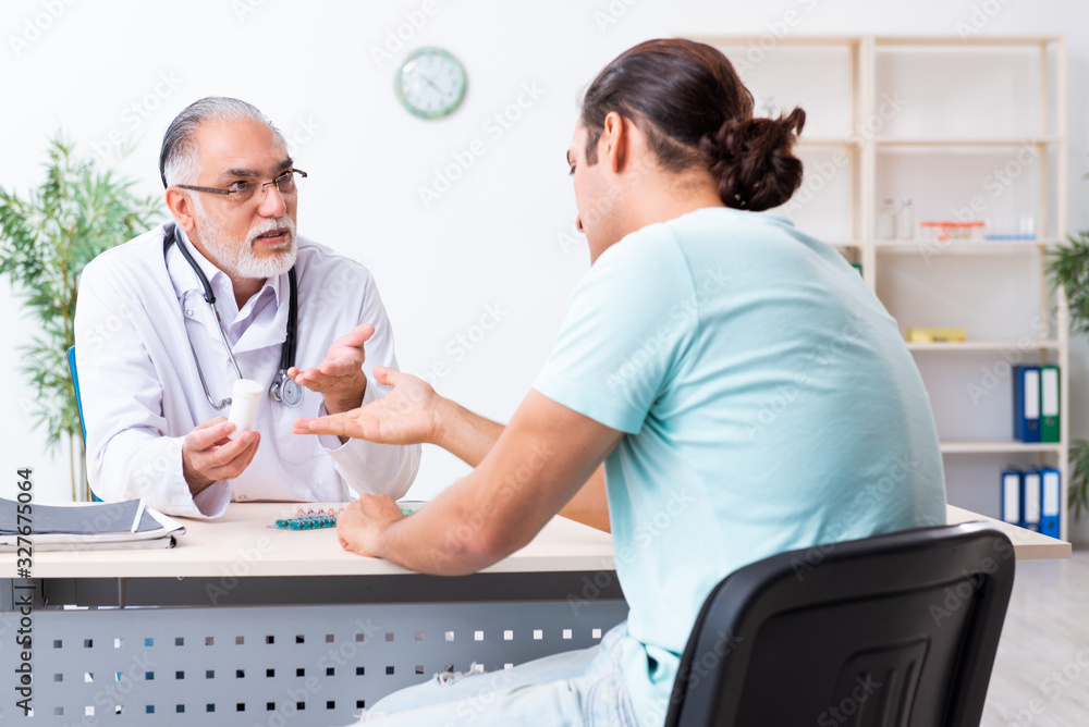 Young man visiting old male doctor