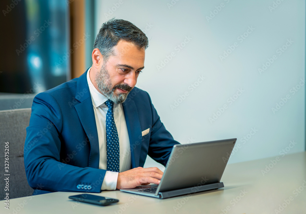 A suit-wearing, bearded and handsome employee who trades on his computer A suit-wearing, bearded and handsome employee who trades on his computer