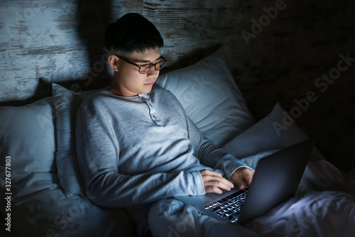 Asian man with laptop in be...