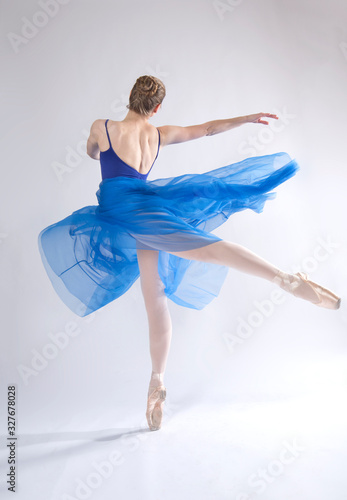Young woman in a blue dress dancing in a studio.