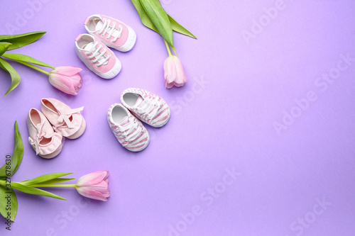 Different baby booties with flowers on color background