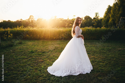 Beautiful young woman in a white wedding dress and black boots at sunset is photographed. © Денис Кипкаев