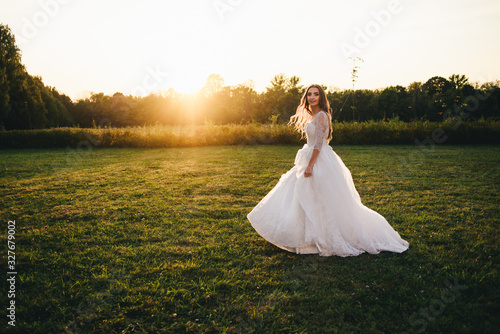 Beautiful young woman in a white wedding dress and black boots at sunset is photographed.