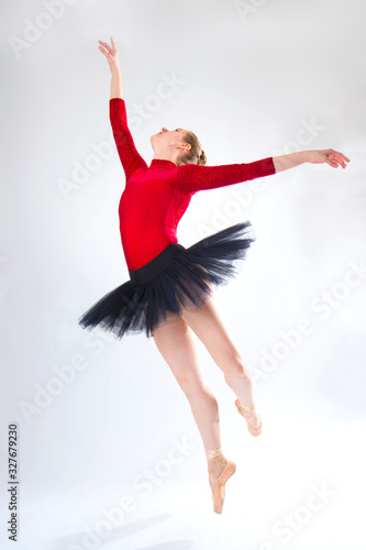 Young woman ballet dancer leaping in a black tutu.