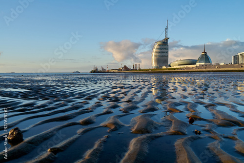 Bremerhaven, Germany - February 03, 2019: Typical buildings of the skyline seen from the mud flat at low tide with beutifully reflecting vivid blue sky in scenic late afternoon light