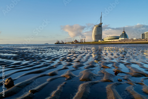 Bremerhaven, Germany - February 03, 2019: Typical buildings of the skyline seen from the mud flat at low tide with beutifully reflecting vivid blue sky in scenic late afternoon light photo