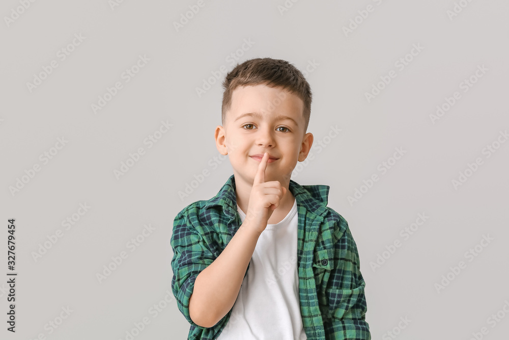 Cute little boy showing silence gesture on grey background Cute little boy showing silence gesture on grey background
