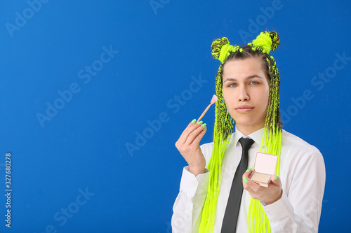Transgender woman applying makeup against color background © Pixel-Shot