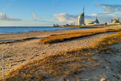 Bremerhaven, Germany - February 03, 2019: beach in late afternoon sunlight in front of vivid blue sky and main bulidings of the skyline