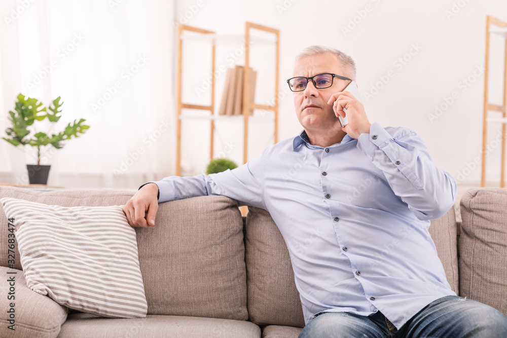 Serious mature man talking on mobile phone at home Serious mature man talking on mobile phone at home